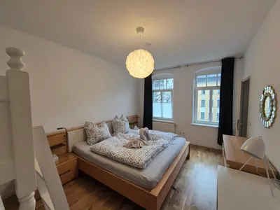Ein Bett oder Betten in einem Zimmer der Unterkunft Chemnitz Saxonia HomeDeLuxe Hochwertige 50qm 2-Zimmer-Ferienwohnung mit privaten Kfz Parkplatz Stellplatz mit MWSt-Rechnung mit XXL Hülsta Bett & Etagenbett mit InternetFlatrate - Ideal für Familien, Paare, Kulturinteressierte & Geschäftsreisende!